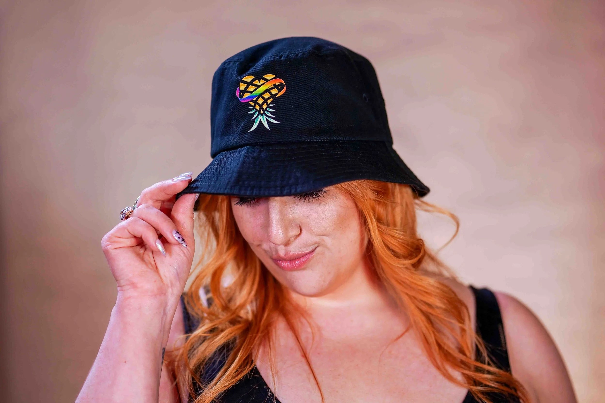 Woman wearing a black bucket hat with upside down Pineapple Logo