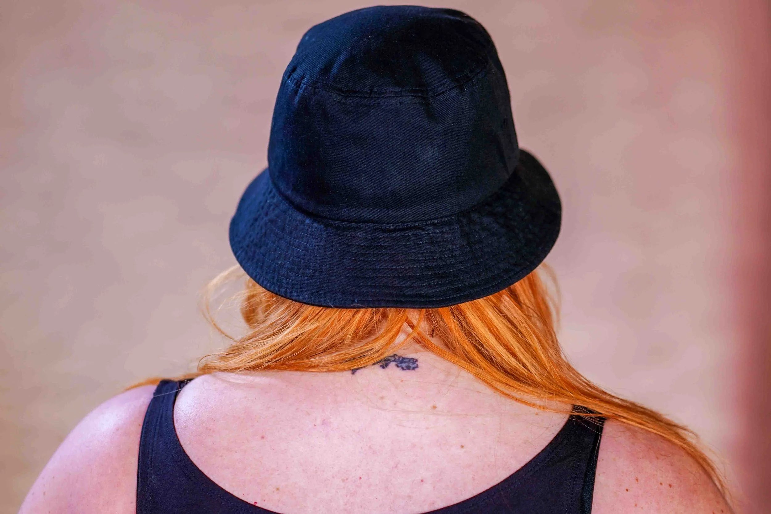 Person wearing a black bucket hat with a blurred background