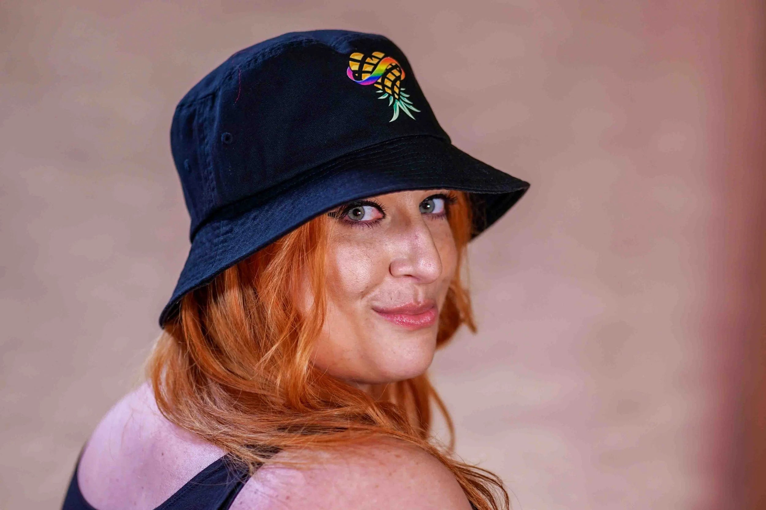 Woman wearing a bucket hat with upside down Pineapple Logo