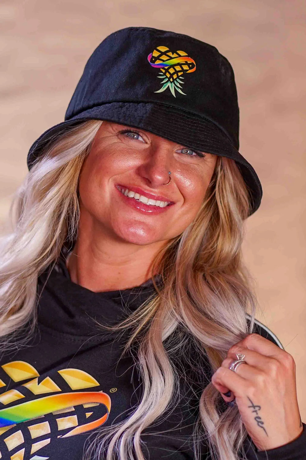 Woman wearing a black bucket hat with upside down Pineapple Logo