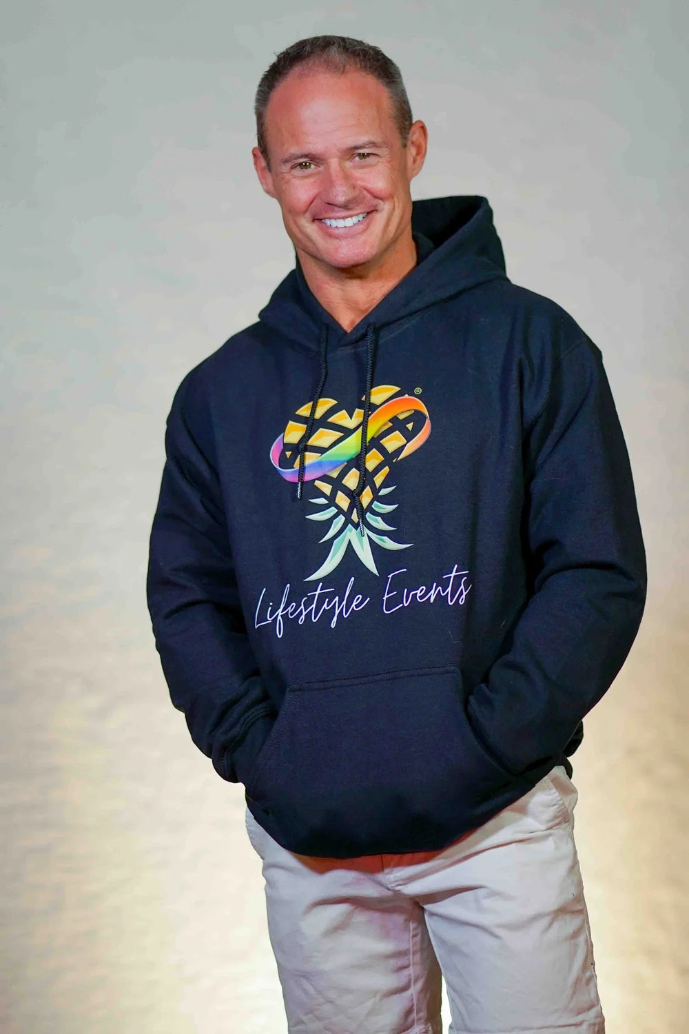Man wearing a navy Upsidedown Pineapple logoed hoodie with a colorful graphic and 'Lifestyle Events' text on a light gray background