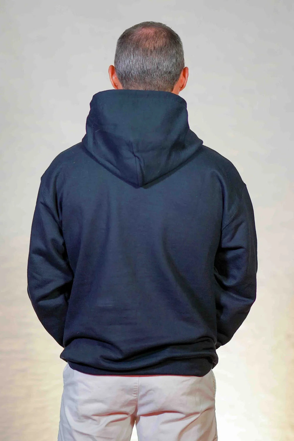 Person wearing a navy blue hoodie from behind on a plain background