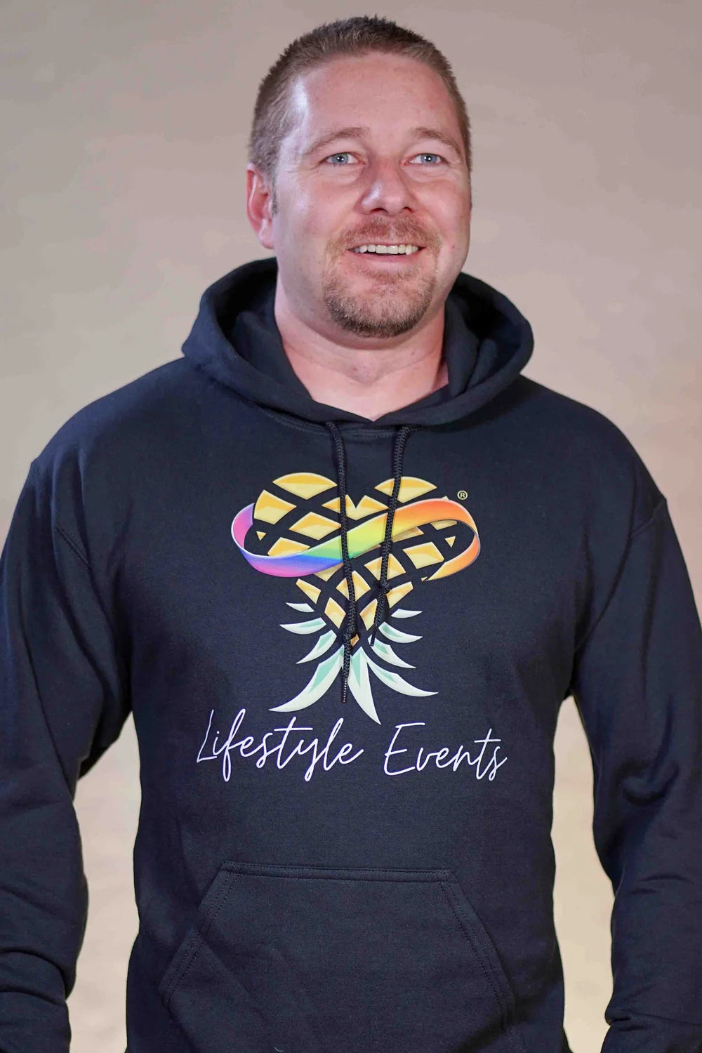 Man wearing a black hoodie with a colorful design and 'Lifestyle Events' text and Upsidedown Pineapple Logo
