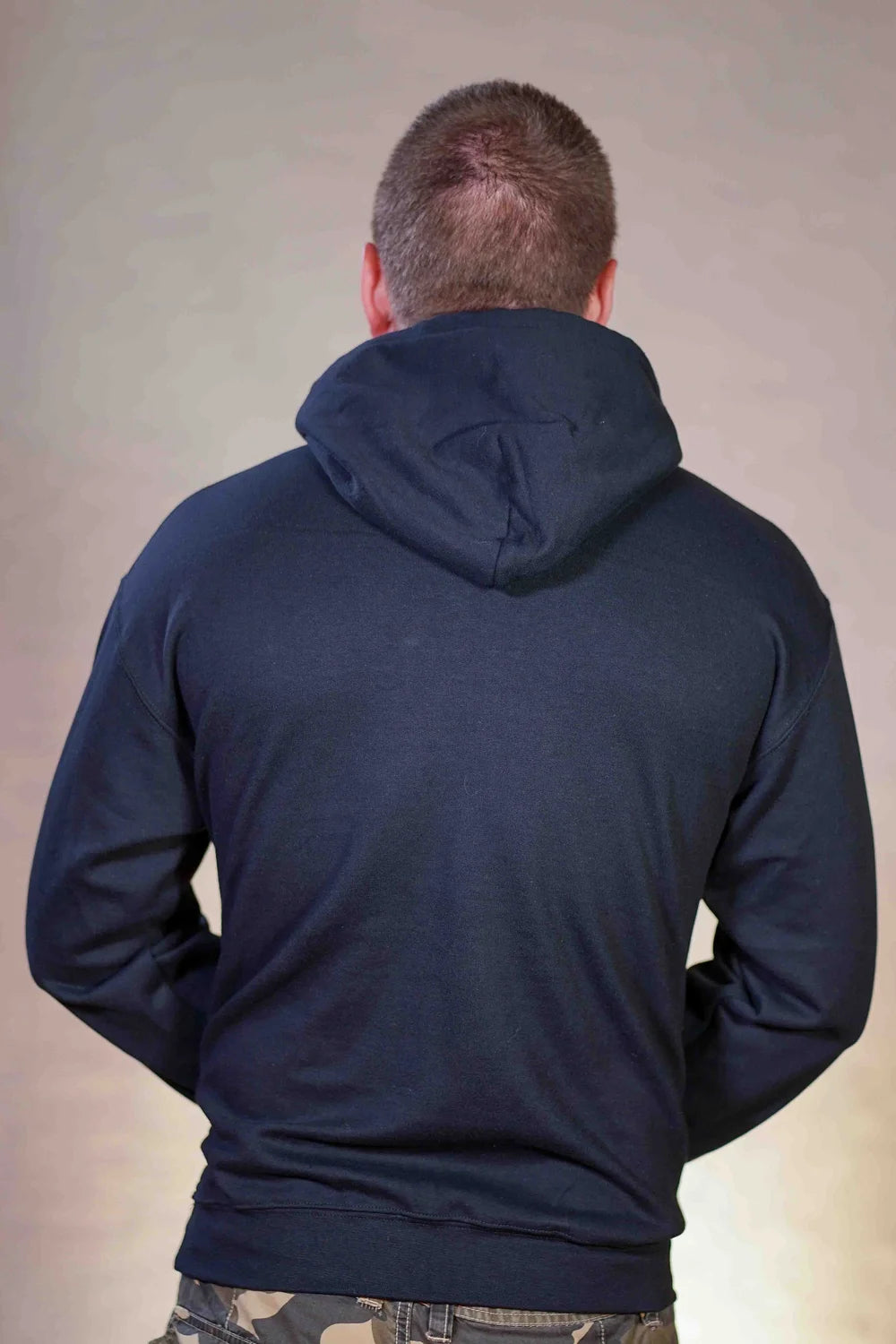 Man wearing a navy blue hoodie from behind on a plain background