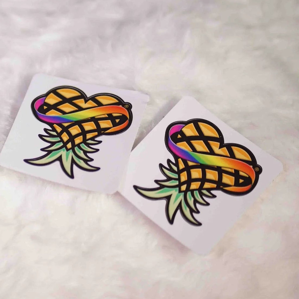 Four colorful pineapple-shaped stickers on a white surface